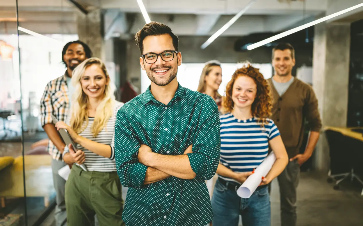 Mitarbeitende stehen lächelnd im Büro