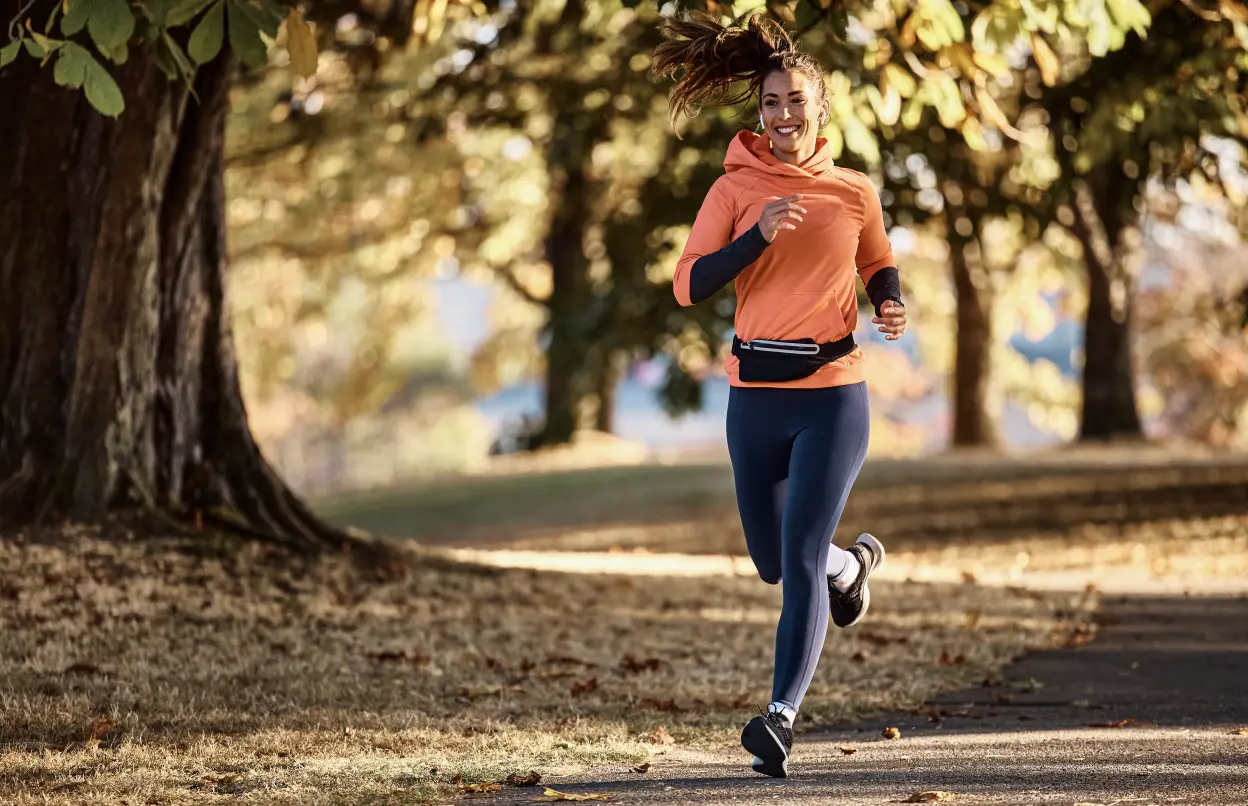 Frau joggt gut gelaunt im herbstlichen Park