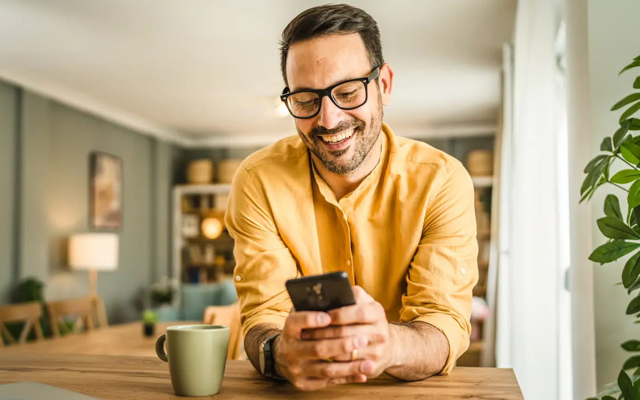 Mann schaut lächelnd auf sein Smartphone