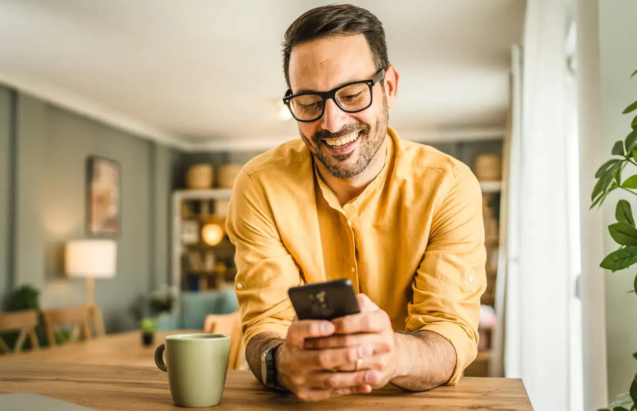 Mann schaut lächelnd auf sein Smartphone