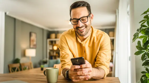 Mann schaut lächelnd auf sein Smartphone
