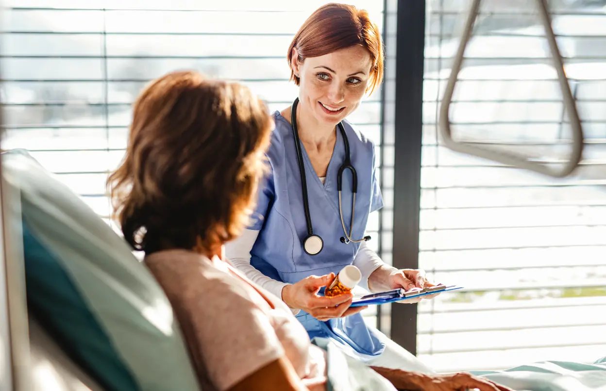 Patientin im Krankenbett wird von Ärztin beraten und versorgt