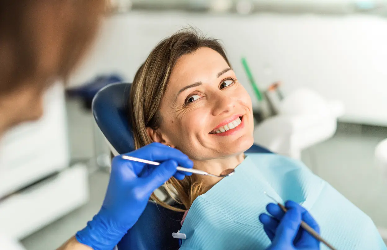 Frau wird vom Zahnarzt mit Spiegel untersucht