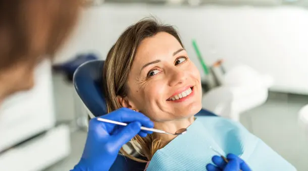 Frau wird vom Zahnarzt mit Spiegel untersucht