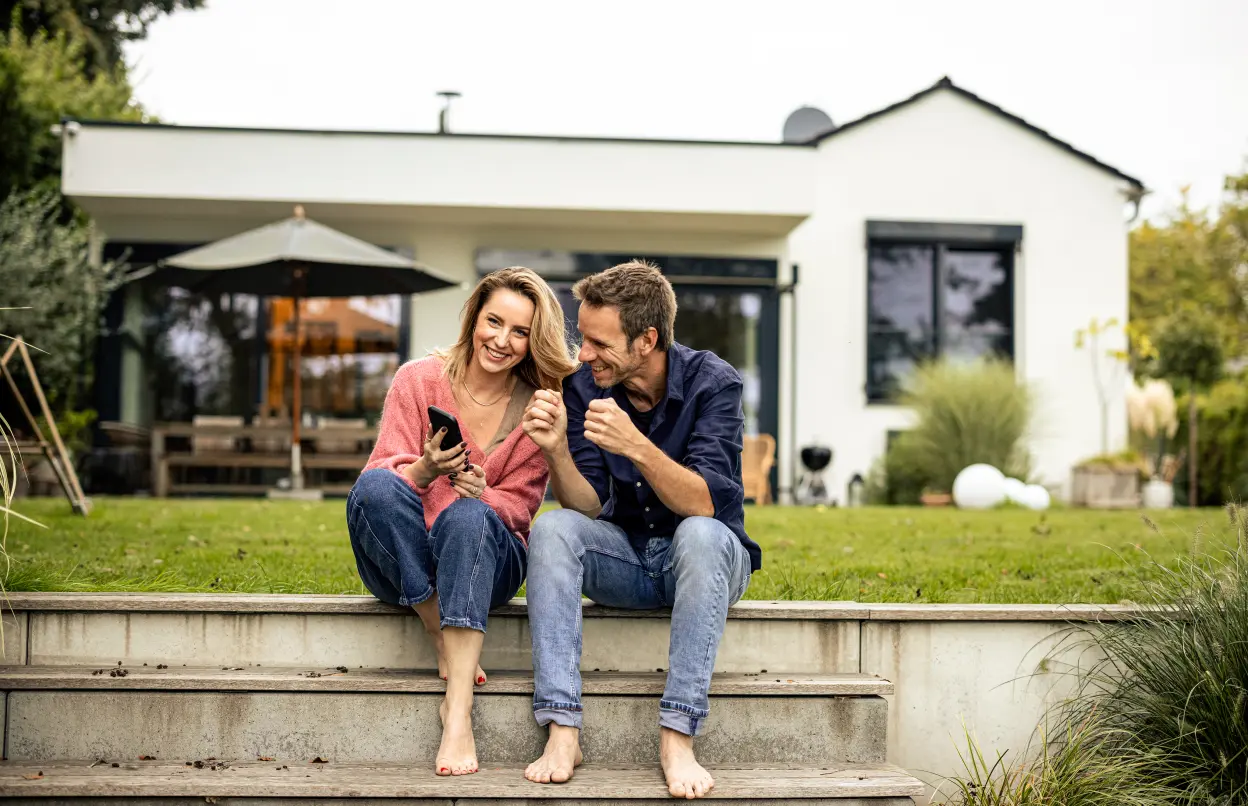 Paar sitzt auf Stufe vor gemeinsamem Haus