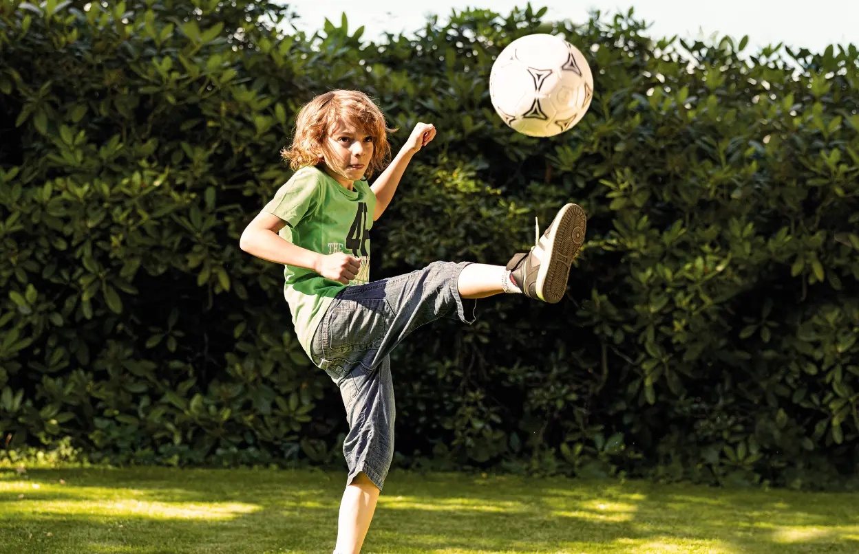 Kind spielt im Garten Fußball