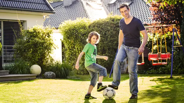 Vater und Sohn spielen im Garten Fußball
