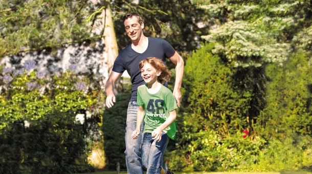 Vater spielt mit Sohn im Garten Fußball