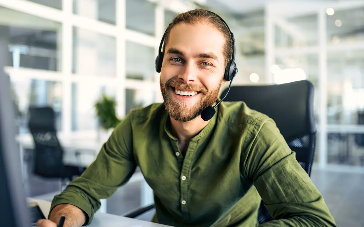 Mann mit Headset telefoniert am Arbeitsplatz