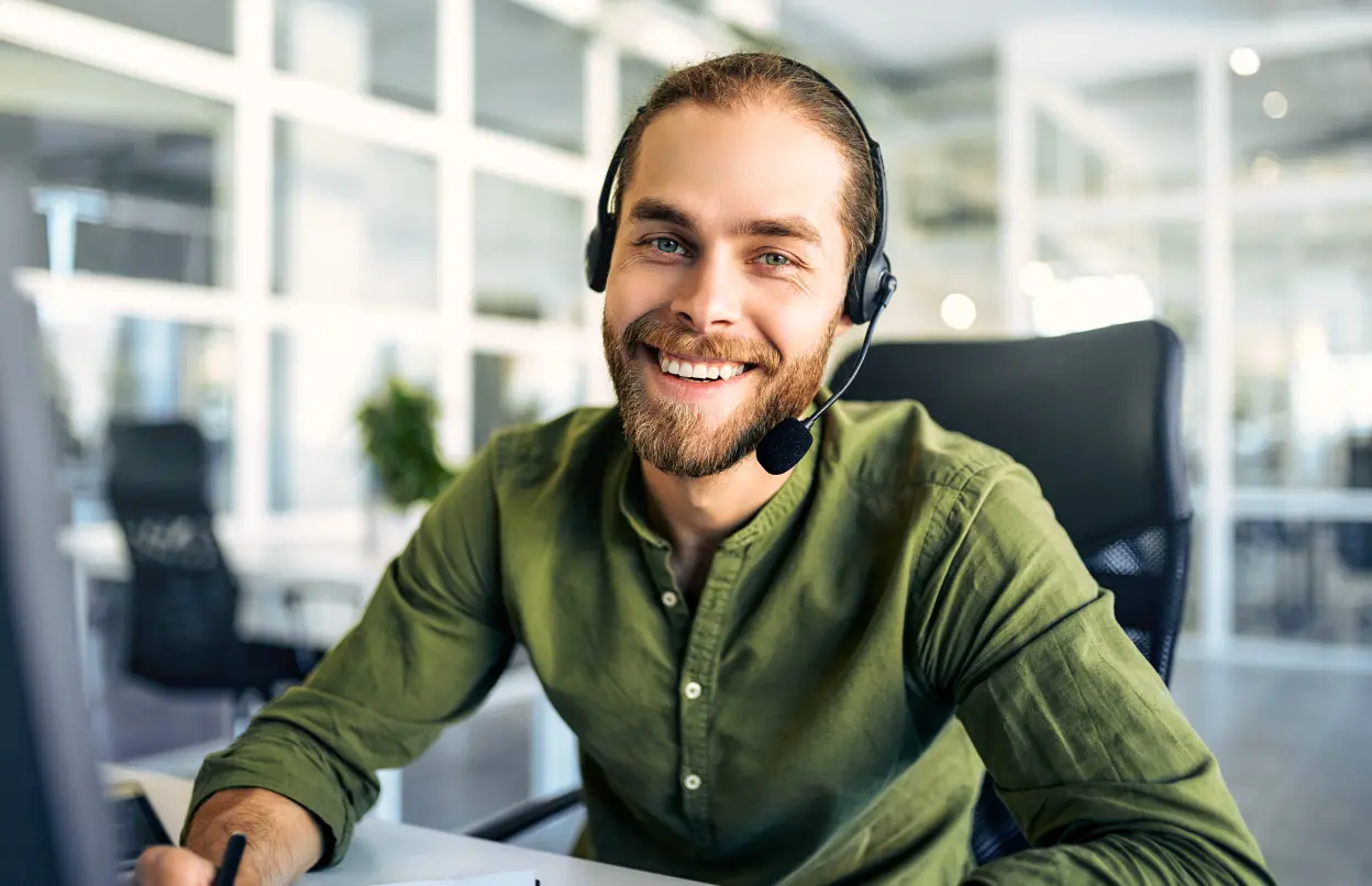 Mann mit Headset telefoniert am Arbeitsplatz