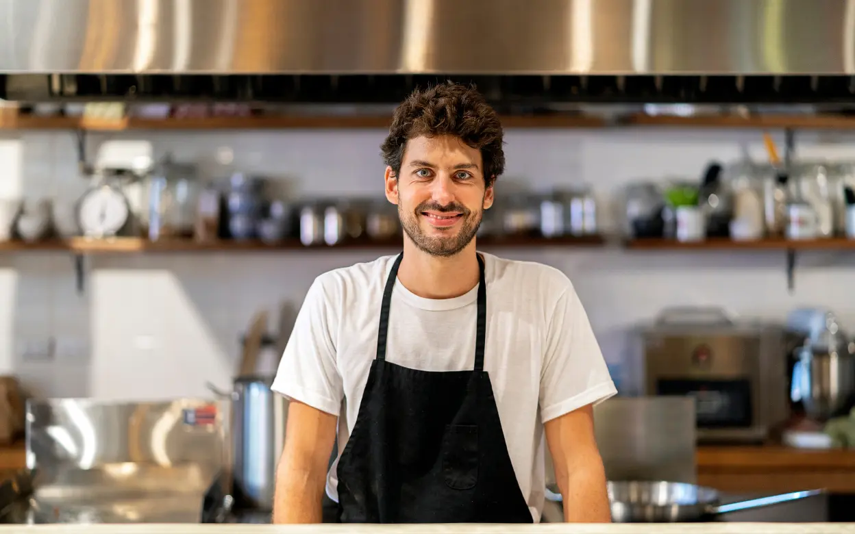Lächelnder Koch steht in seiner Restaurantküche