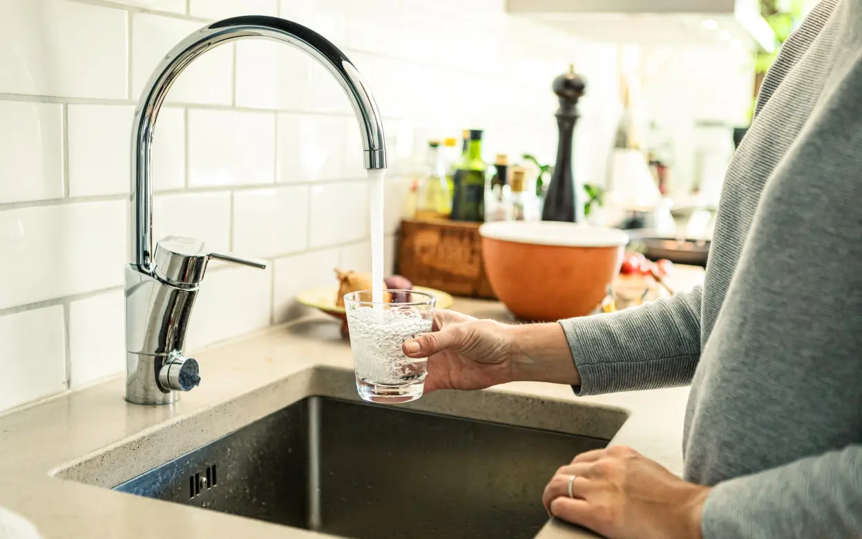 Eine Person füllt ein Glas mit Leitungswasser.