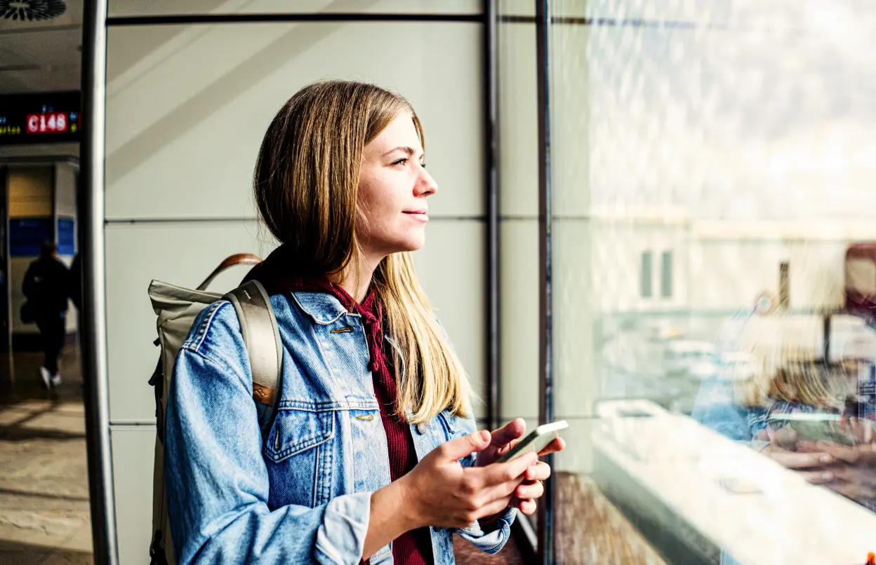 Eine Frau wartet am Flughafen und schaut aus dem Fenster.