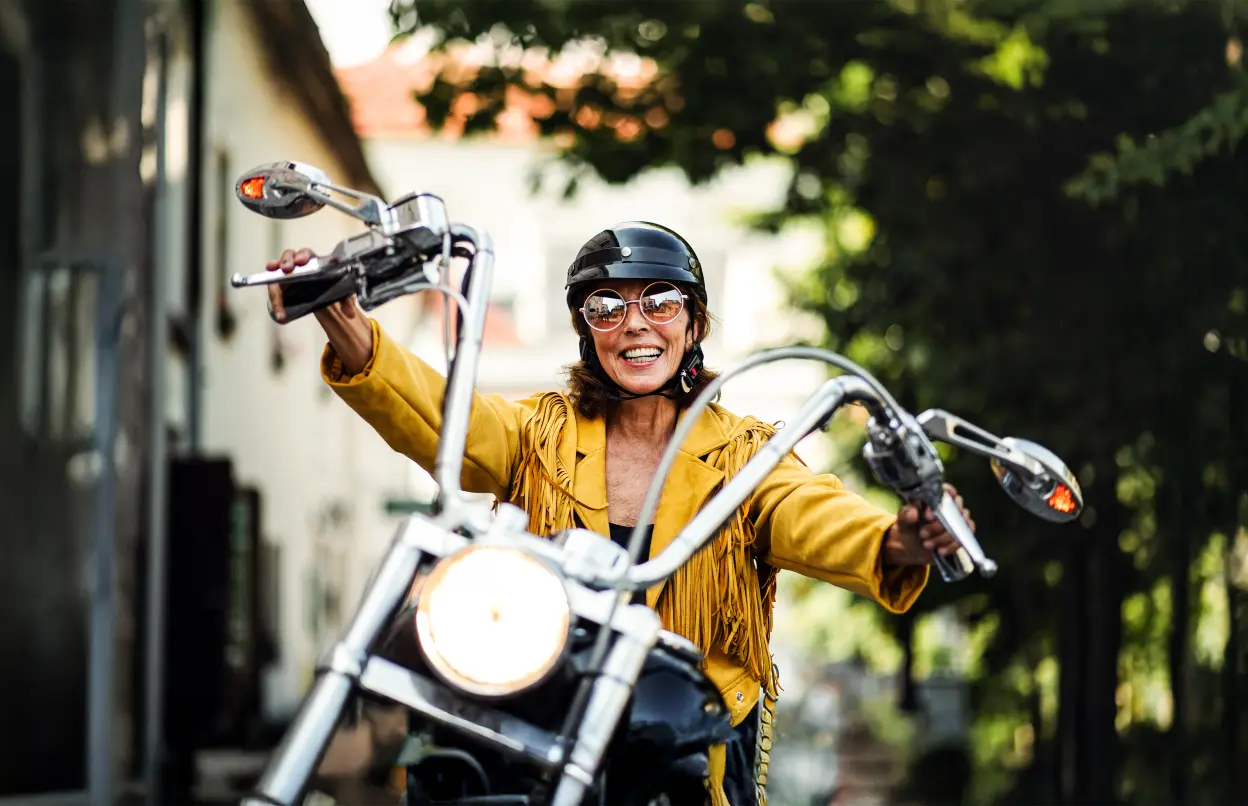 Lächelnde Frau sitzt auf Motorrad | © halfpoint/stock.adobe.com Lächelnde Frau sitzt auf Motorrad
