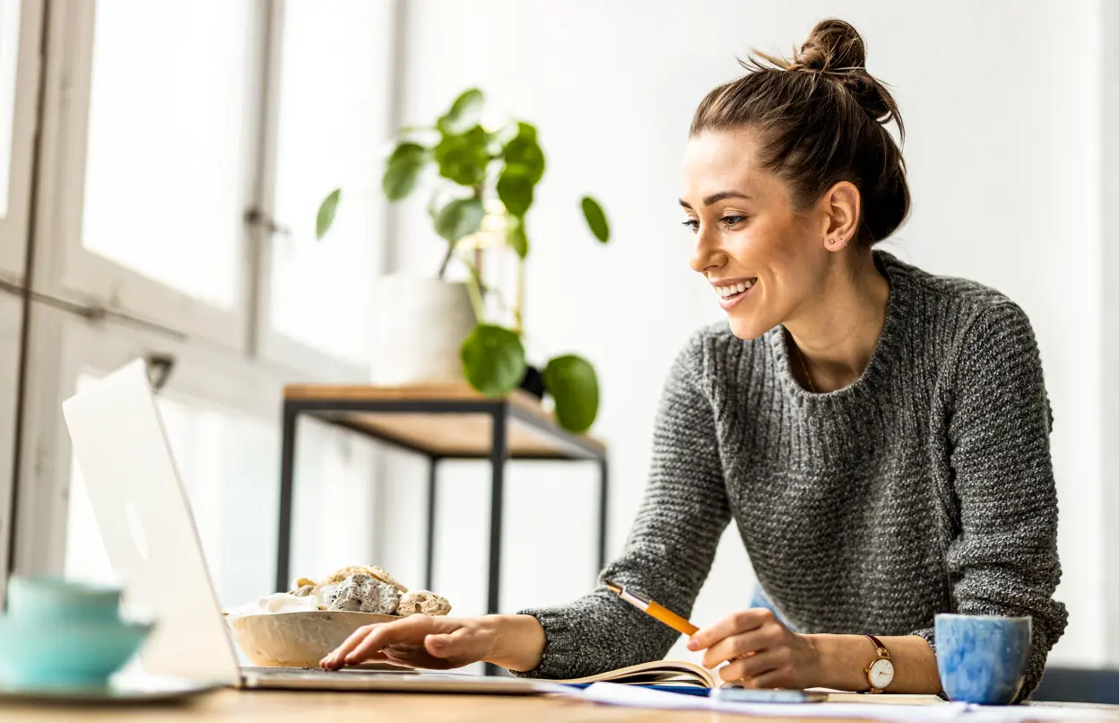 Frau sitzt lächelnd vor dem Laptop