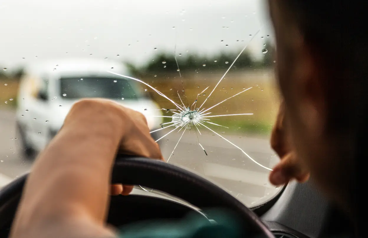 Mann starrt auf Steinschlag in der Windschutzscheibe 