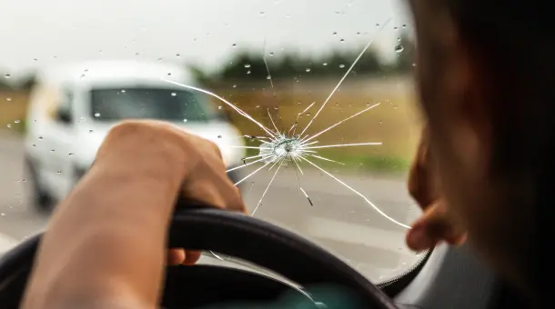 Mann starrt auf Steinschlag in der Windschutzscheibe 