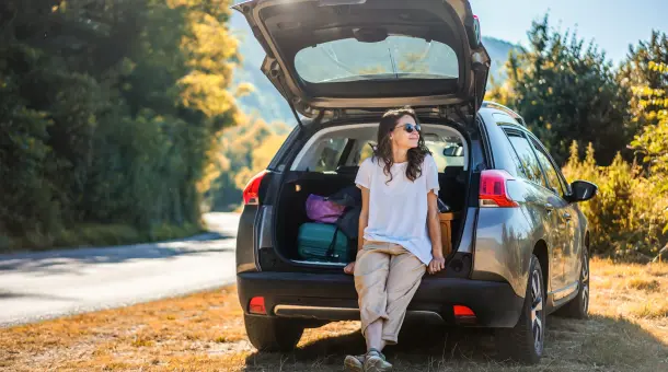 Zufriedene Frau an Kofferraum gelehnt