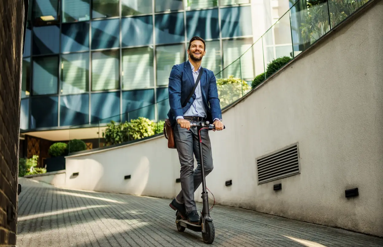 Mann fährt gut gelaunt E-Scooter