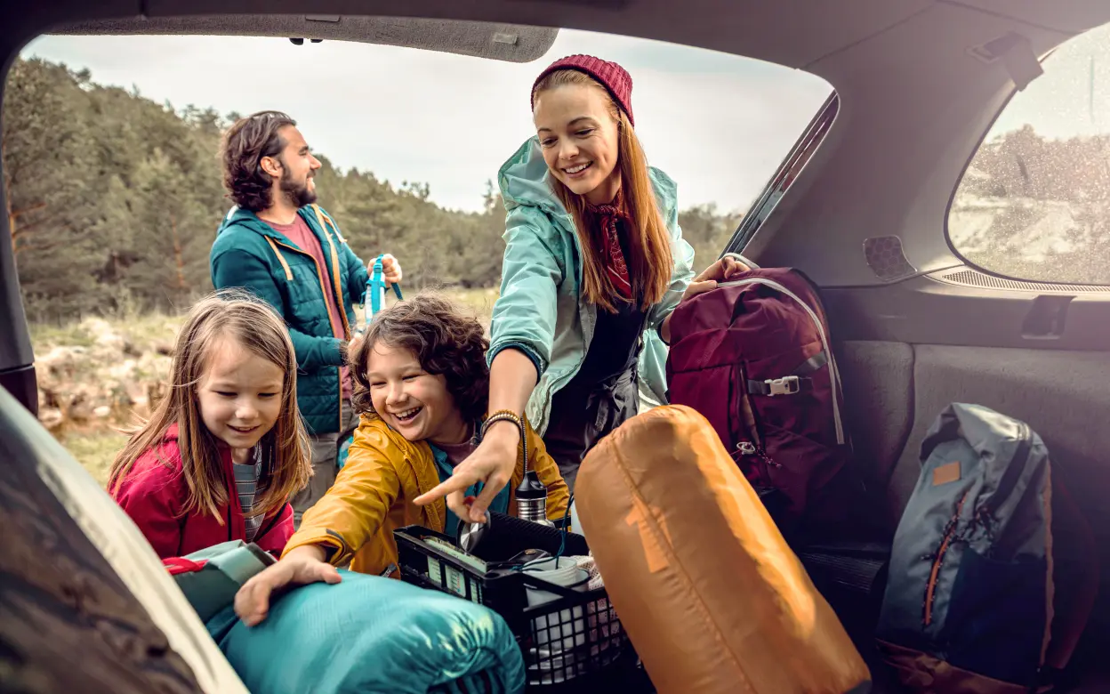 Familie entlädt Campingsachen aus dem Kofferraum 