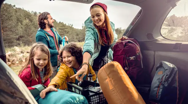 Familie entlädt Campingsachen aus dem Kofferraum 