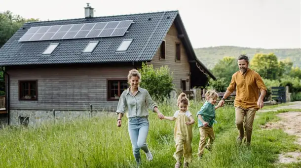 Eine glückliche Familie vor einem Haus mit Photovoltaikanlage auf dem Dach
