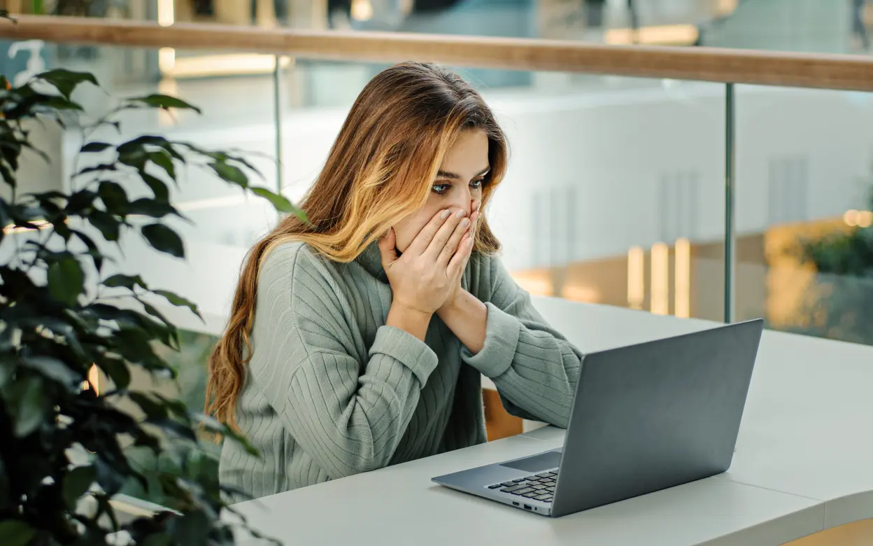 Frau sieht schockiert auf ihren Laptop