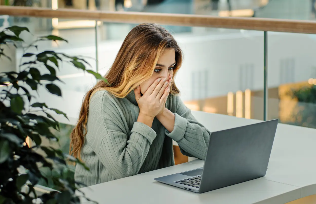Frau sieht schockiert auf ihren Laptop