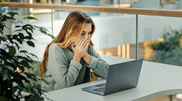 Frau sieht schockiert auf ihren Laptop
