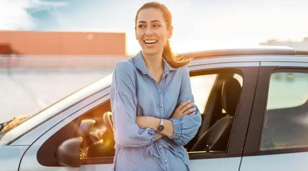 Frau steht lächelnd an Autotür