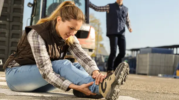 Frau hält sich nach Sturz den Knöchel