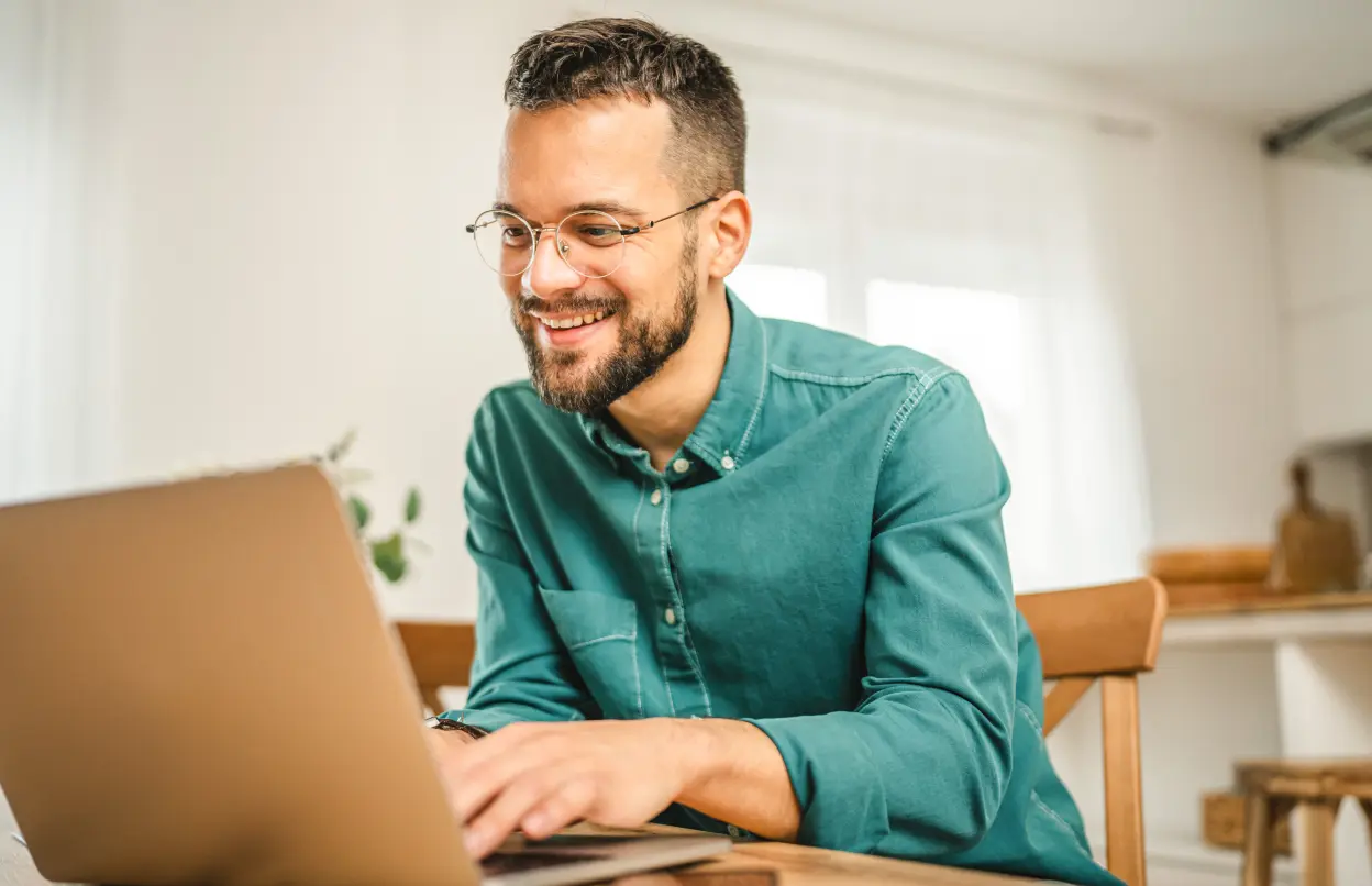 Mann sitzt gut gelaunt vor Laptop