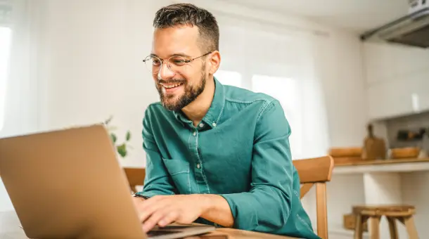 Mann sitzt gut gelaunt vor Laptop