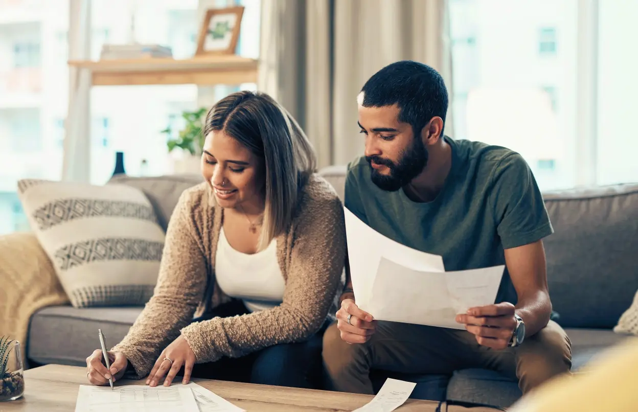 Paar sitzt auf Sofa und unterzeichnet Vertrag