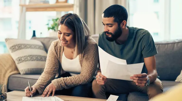 Paar sitzt auf Sofa und unterzeichnet Vertrag