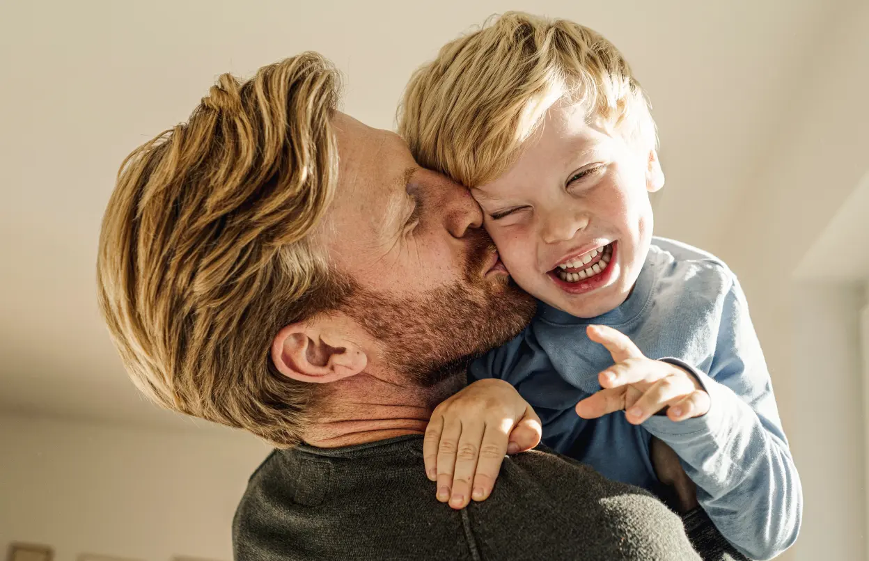 Vater küsst seinen lachenden Sohn