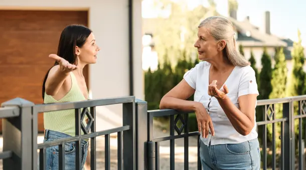 Zwei Frauen diskutieren miteinander vor Wohnhaus