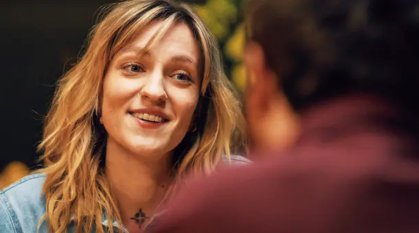 Eine Frau lächelt eine:n Gesprächspartner:in an.