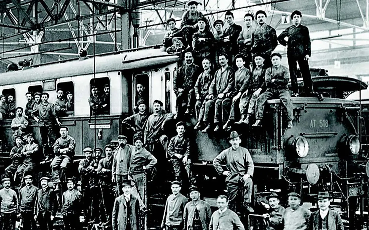 Auf der historischen Aufnahme sind Eisenbahner vor einer Lokomotive zu sehen.