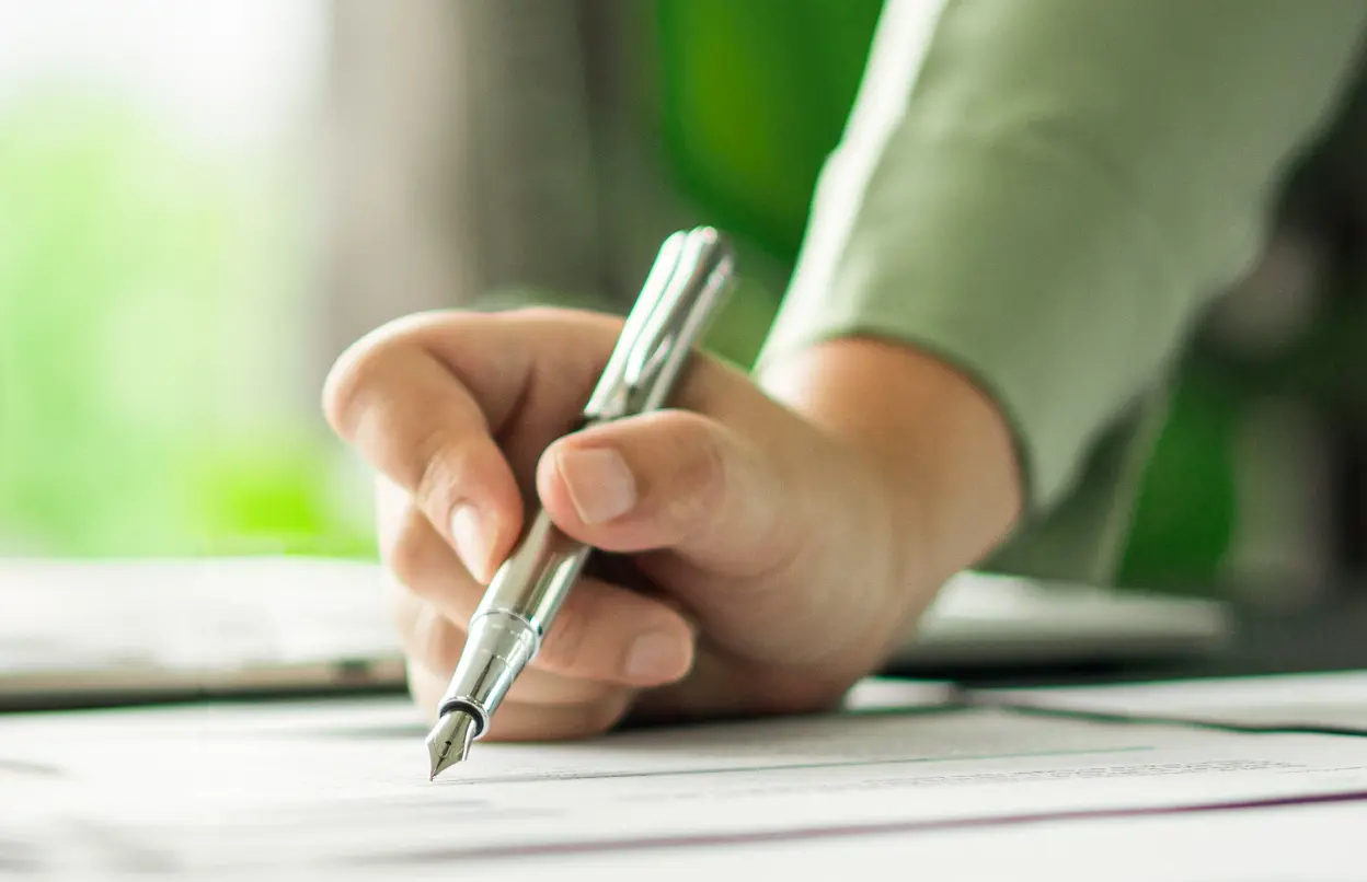 Eine Person hält einen Füller in der Hand.