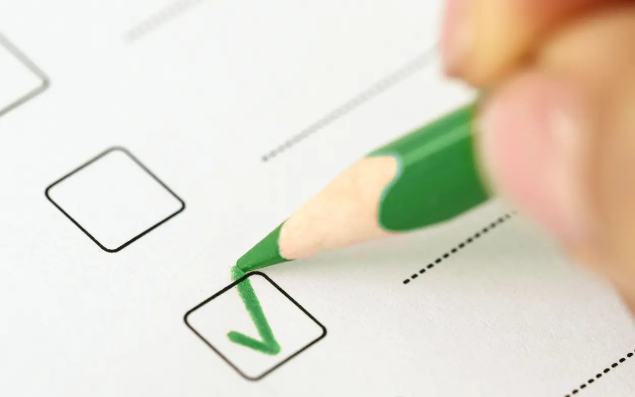 Eine Person notiert in grüner Farbe einen Haken.