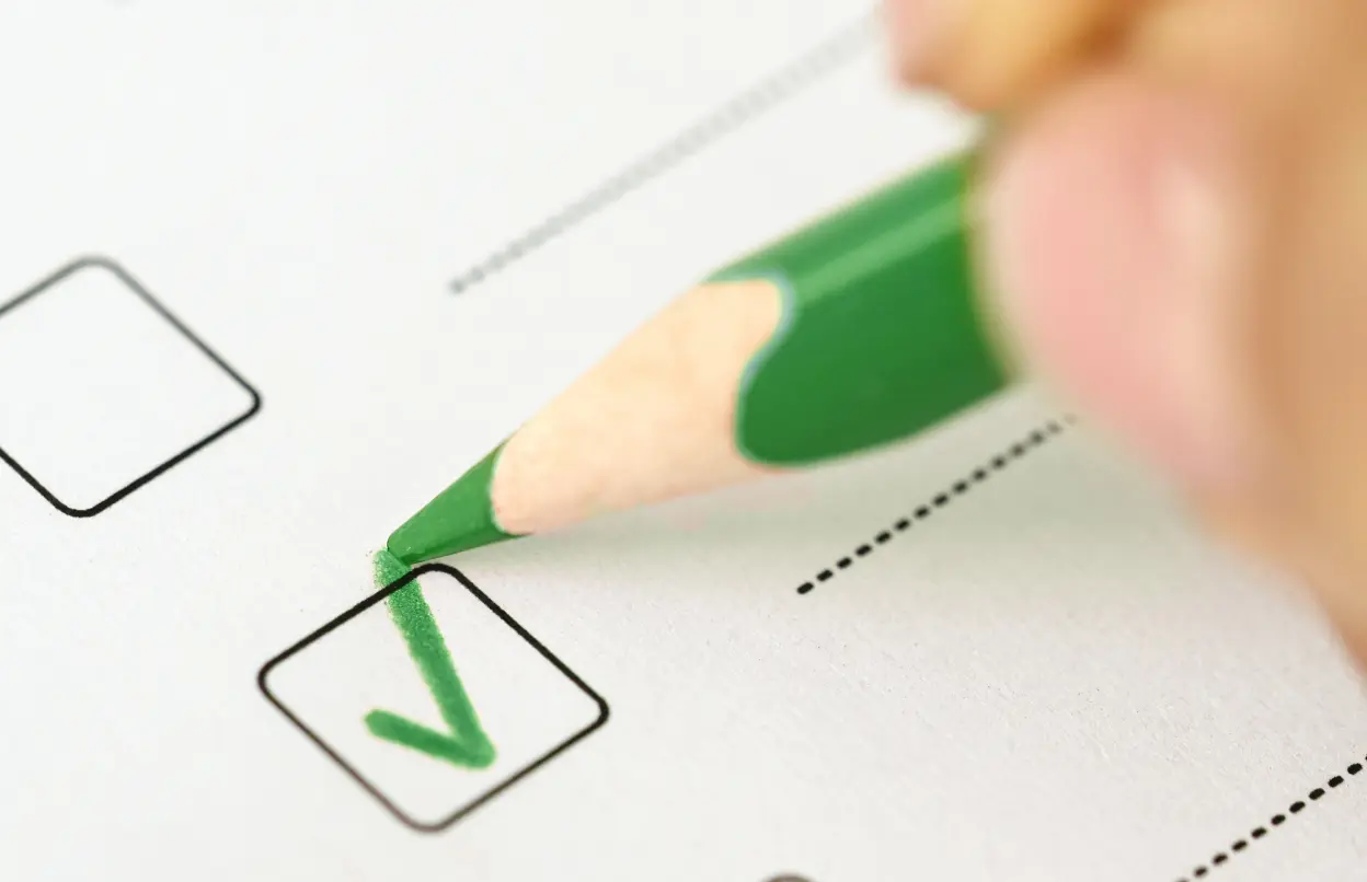 Eine Person notiert in grüner Farbe einen Haken.