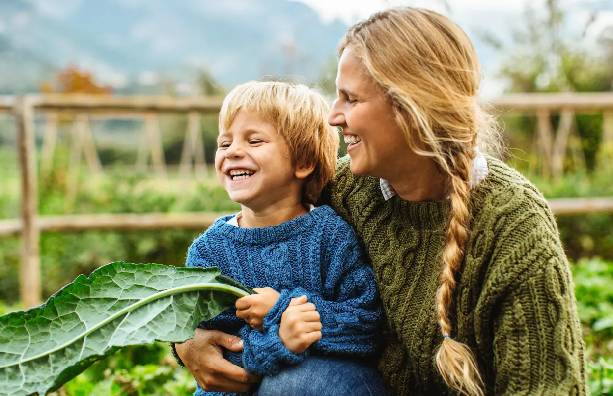 Frau und Kind lachen gemeinsam im Gemüsegarten