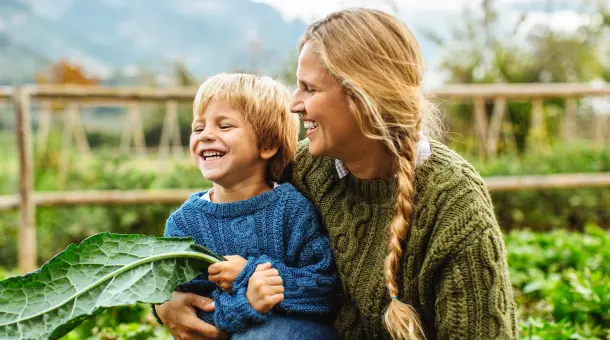 Frau und Kind lachen gemeinsam im Gemüsegarten