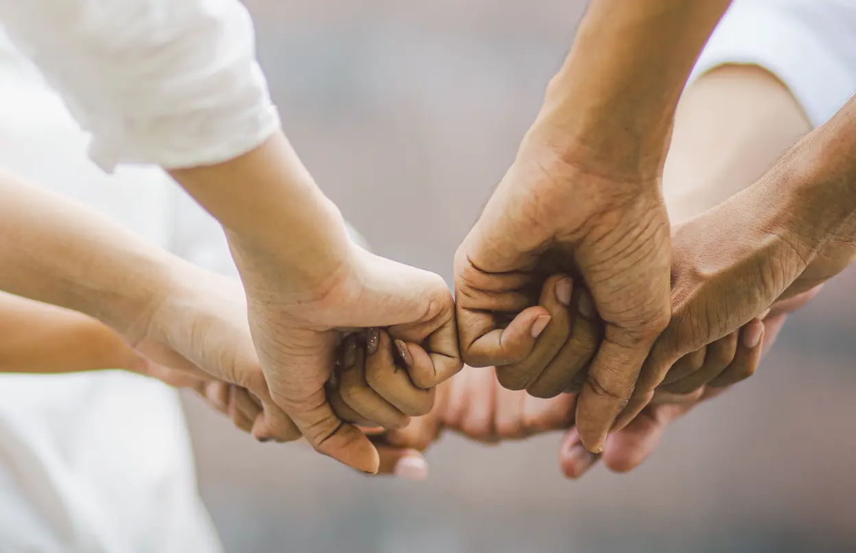Mehrere Personen halten ihre Fäuste aneinander.