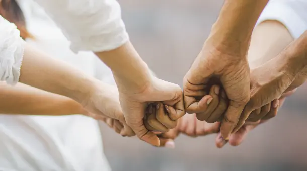 Mehrere Personen halten ihre Fäuste aneinander.